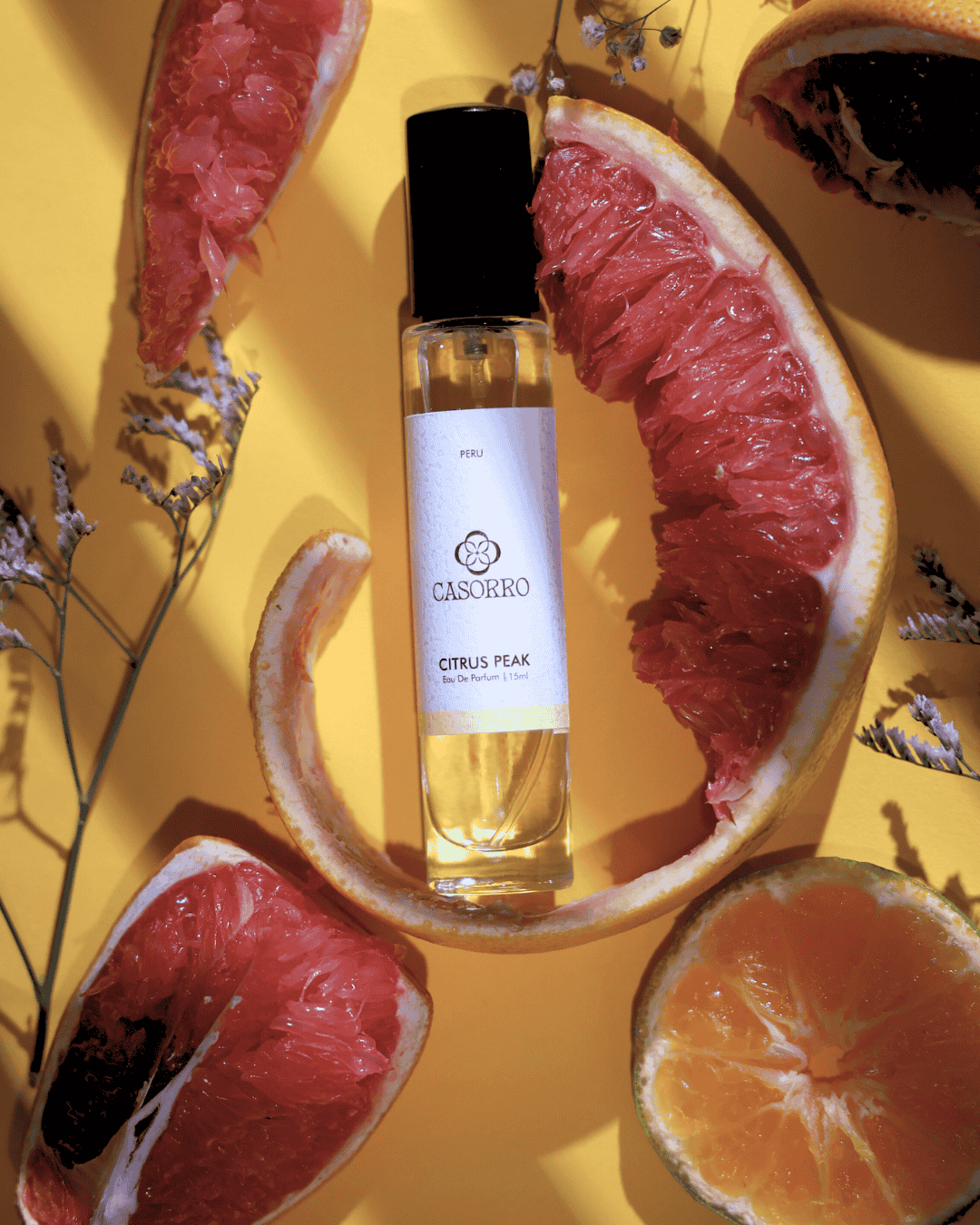 Casorro citrus peel perfume bottle surrounded by sliced grapefruits on a yellow background
