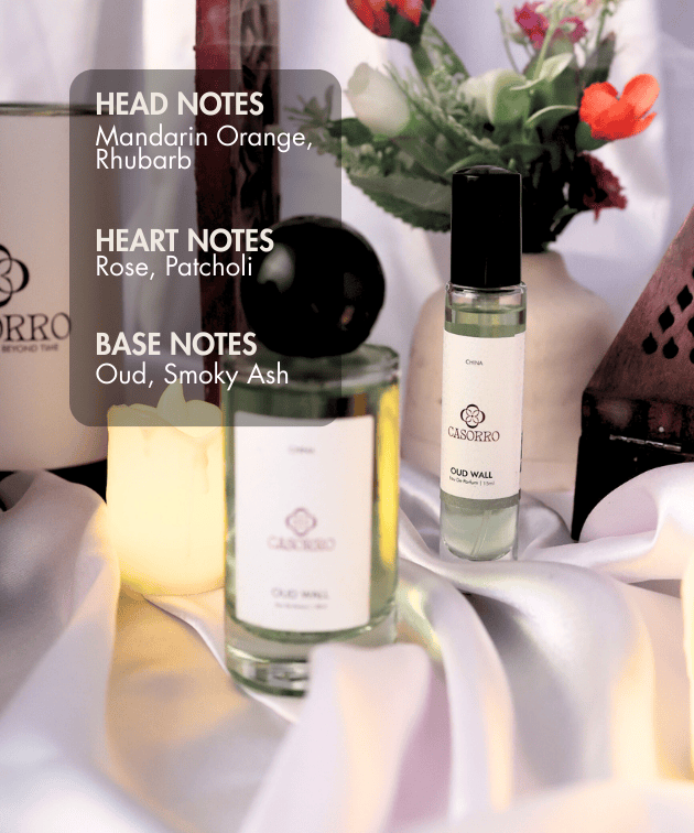 Two bottles of Casorro perfume with floral arrangement and candles on a soft white background