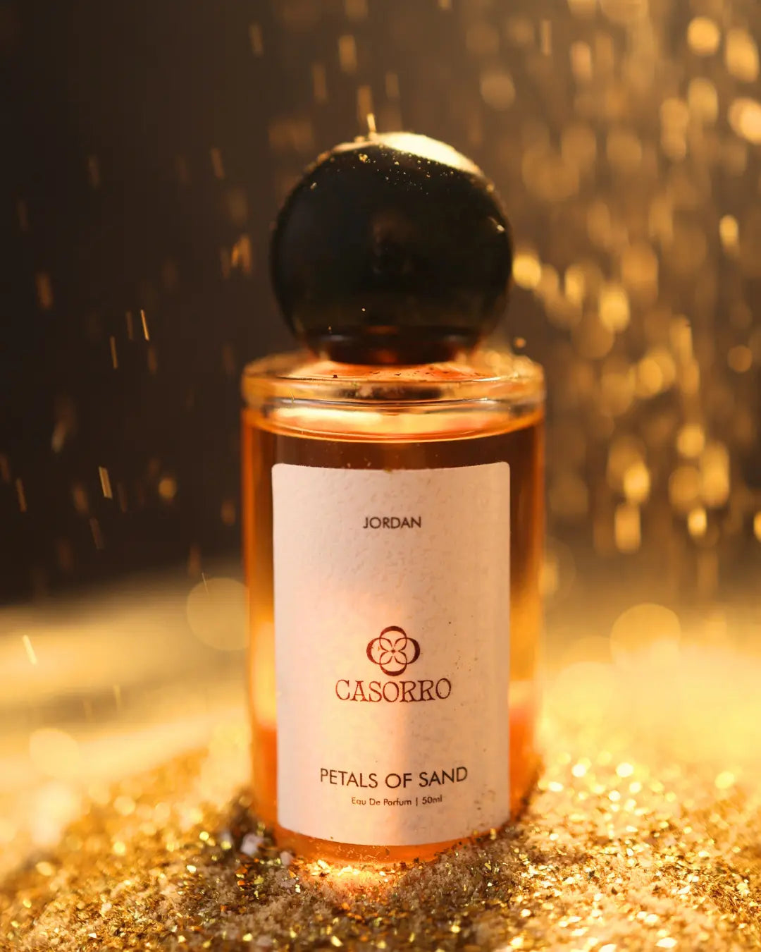 CASORRO- Petals of Sand perfume bottle on a glittery surface with a blurred background